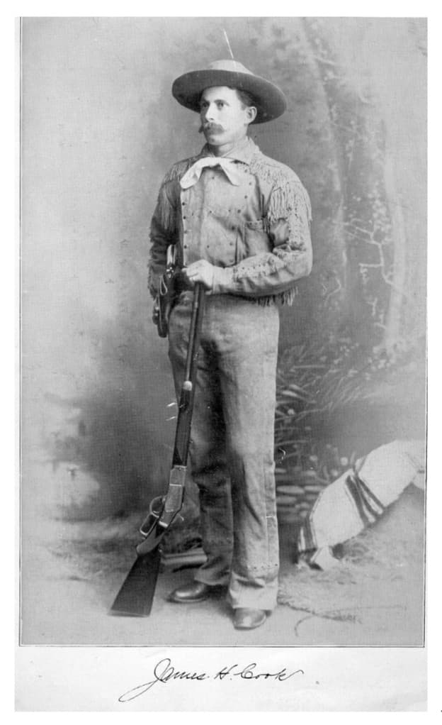 Studio portrait of James H. Cook with rifle